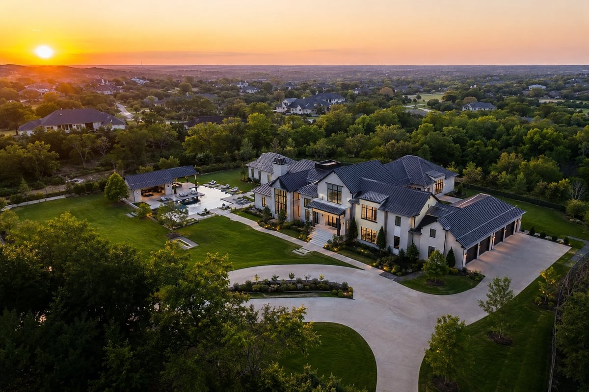 Aerial view of a large modern home with pool at sunset overlooking a residential neighborhood